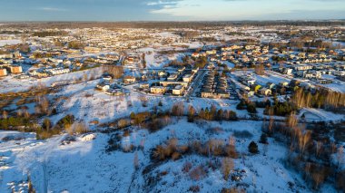 Birkaç çok katlı evin ve kış güneşli bir günde karla kaplı otoparkın insansız hava aracı fotoğrafları.