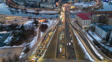 Kış bulutlu bir günde kar ve nehirle kaplı ana caddeden geçen insansız hava aracı fotoğrafları.