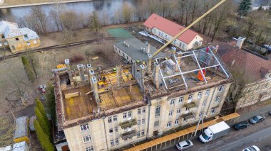 Güneşli bahar aylarında eski binanın çatısına yeni çatı inşa eden inşaat işçilerinin insansız hava aracı fotoğrafları.