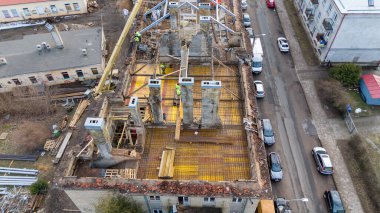 Güneşli bahar aylarında eski binanın çatısına yeni çatı inşa eden inşaat işçilerinin insansız hava aracı fotoğrafları.