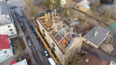 Güneşli bahar aylarında eski binanın çatısına yeni çatı inşa eden inşaat işçilerinin insansız hava aracı fotoğrafları.