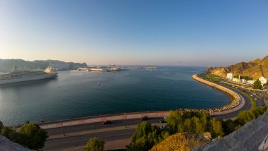 Umman 'da bir körfezin fotoğrafı, Muscat eski kasabasında güneşli bir bahar akşamında teknelerle çekilmiş.