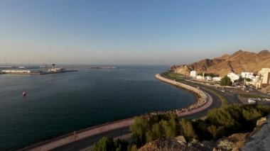 Umman 'da bir körfez görüntüsü, Muscat eski kasabası, araba trafiği ve tekneler ile güneşli bahar akşamları.