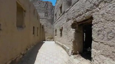 Güneşli baharda Umman 'ın Nizwah kenti yakınlarındaki terk edilmiş kerpiç köyünün fotoğrafları.