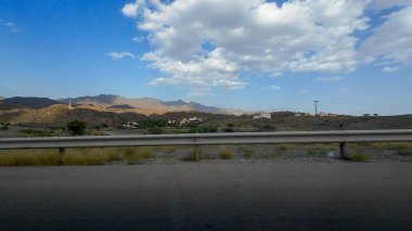 Umman 'daki kurak dağlık arazinin güneşli bahar günlerinde bir arabadan çekilmiş fotoğrafı.
