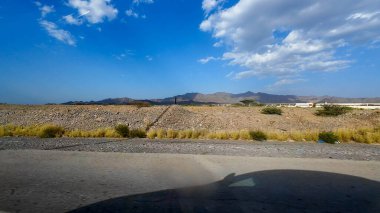Umman 'daki kurak dağlık arazinin güneşli bahar günlerinde bir arabadan çekilmiş fotoğrafı.