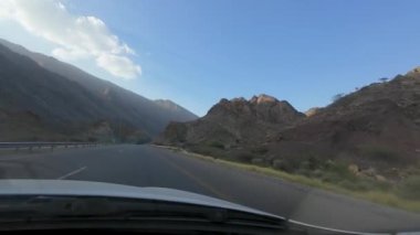 Umman 'daki kurak dağ manzarasının güneşli bahar gününde bir arabadan çekilmiş görüntüsü.