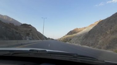 Umman 'daki kurak dağ manzarasının güneşli bahar gününde bir arabadan çekilmiş görüntüsü.