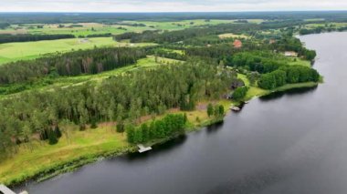 Yaz bulutlu bir günde göl, orman ve yakınlarındaki evlerin insansız hava aracı görüntüleri.