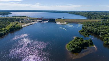Güneşli yaz gününde barajın üzerinden geçen bir su barajının, ormanın ve yolun insansız hava aracı fotoğrafları.