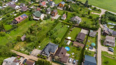 Güneşli yaz günlerinde etrafı ormanla çevrili küçük bir kasabanın insansız hava aracı fotoğrafları.