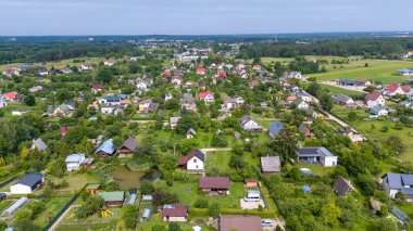 Güneşli yaz günlerinde etrafı ormanla çevrili küçük bir kasabanın insansız hava aracı fotoğrafları.