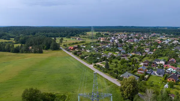 stock image Drone photography of small town and electric lines going through it surrounded by forest during summer sunny day