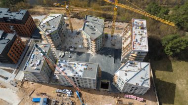 Güneşli yaz günlerinde bir şehirde inşaat şantiyesi ve inşaat makinelerinin insansız hava aracı fotoğrafları