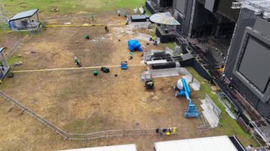 Gönüllülerin çöpleri temizlediği ve insanların bulutlu yaz gününde müzik festivalinden sonra müzik sahnelerini söktüğü insansız hava aracı görüntüleri.