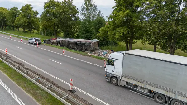 Otoyoldaki bir kamyon kazasının hava görüntüsü. Yolda kırmızı bir kamyon var, enkaz parçaları etrafa saçılmış. Yol kenarında inşaat konileri görülebiliyor.