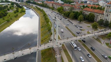 Nehir üzerindeki bir yaya köprüsünün havadan görünüşü ve yaz güneşli bir günde insanlar üzerinde yürüyor.