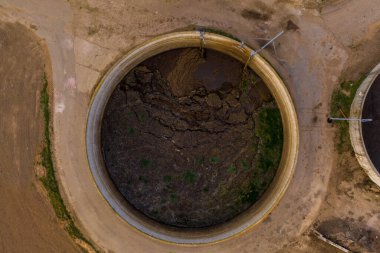 Çatlamış kuru toprak ve içinde yeşil yamalar olan büyük dairesel bir tankın havadan görüntüsü. Çevresi çorak, bu da kuru bir çevreye işaret ediyor..