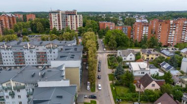 Konut ve apartman binalarının karışımının yer aldığı bir banliyö bölgesinin havadan görüntüsü. Manzara yeşillik ve kentsel yapıları içerir.,