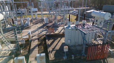 Çeşitli trafolar, devre kesiciler ve elektrik hatlarının yer aldığı endüstriyel bir elektrik santrali. Sahne açık gökyüzü ve güneş ışığı ile açılır..