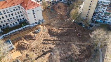 Binalar ve araçlar arasındaki kentsel alandaki bir peyzaj şantiyesinin hava görüntüsü.