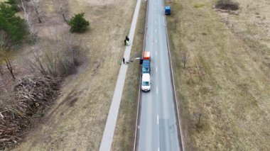 Yol boyunca park etmiş iki aracın hava görüntüsü. Bir grup insan kaldırımın altındaki boru hattını onarıyor ve zeminde bazı ekipmanlar görülüyor. Trafik konileri yola koyulur..