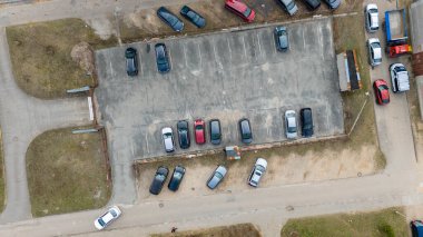 Düzenli bir şekilde park edilmiş eski bir otoparkın havadan görüntüsü. Arazi birkaç çimen ve bir yol ile çevrili..