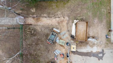 Bir yerleşim yerinin yanındaki inşaat alanının havadan görüntüsü. Bölge, işçiler ve cadde boyunca park halindeki çok sayıda araçla yenileniyor. Zemin kısmen kazılmış..