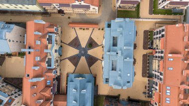 Aerial view of a residential complex with modern buildings featuring red and blue roofs, courtyards, and pathways. clipart