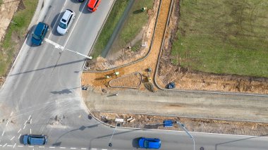Yol kenarında işçilerin ve ekipmanların bulunduğu inşaat halindeki kaldırım manzarası.