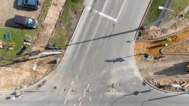Yol kenarında işçilerin ve ekipmanların bulunduğu inşaat halindeki kaldırım manzarası.