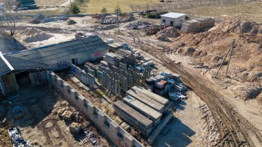 Eski beton yığınlarının hava manzarası depolama alanı, toprak yığınları ve birkaç küçük bina. Bölge bir çitle çevrili ve yerde görünür lastik izleri var..