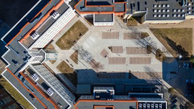 Binalarla çevrili merkezi bir avlusu olan modern bir eğitim kurumunun havadan görüşü. Yerleşim yeri geometrik ve organize, yeşil alanları ve yolları gösteriyor.