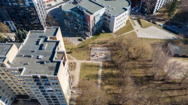 Apartman binaları ve ağaçlarla çevrili küçük çocuk parkı olan kentsel yerleşim alanı..