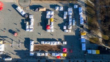 Festival ve binalar sırasında sokak pazarı olan bir şehir manzarası.