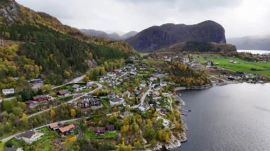 Evleri, yeşil tarlaları ve marinası olan pitoresk bir sahil köyünün havadan görünüşü. Manzarada yerleşim evleri, ağaçlar ve kırsal kesimde yaşamanın güzelliğini gösteren bir su kütlesi yer alıyor..