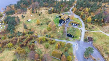 Ağaçlar ve çimlerle çevrili yeşil çatıları olan kırsal bir bölgenin havadan görünüşü. Sahnede yollar, yollar ve dağınık banklar, doğa ve mimarinin gösterişli karışımı yer alıyor..