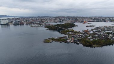 Deniz ve şehir binalarıyla çevrili, adaları birbirine bağlayan bir köprüye sahip bir sahil şehrinin havadan görünüşü bulutlu bir gökyüzünün altında..