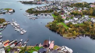 Su ve yeşilliklerle çevrili marinaları, tekneleri ve konutları olan kıyı kasabasının havadan görünüşü.