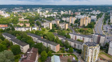 Konut binaları, yeşil parklar ve yolların karışımından oluşan bir banliyö manzarası. Manzarada ağaçlar ve açık alanlarla çevrili çeşitli apartman kompleksleri yer alıyor..