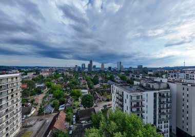 Modern gökdelenleri ve bulutlu bir gökyüzünün altındaki konut binaları olan bir şehir manzarası..