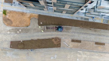 İşçilerin ve yolda bir aracın bulunduğu inşaat alanının havadan görüntüsü..