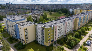 Yeşil alanlar ve ağaçlarla çevrili bir yerleşim yerindeki renkli apartmanların havadan görünüşü.