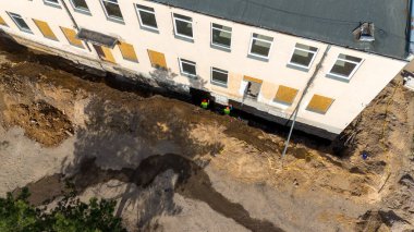 Tahta pencereli ve temeli etrafında inşaat çalışmaları olan bir binanın havadan görünüşü.