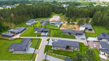 Ayrı evleri, yeşil çimenleri ve çevreleyen ağaçları olan modern yerleşim yerlerinin hava manzarası..