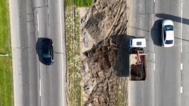 Bir kazıcı ve çöp kamyonuyla yol yapımının havadan görüntüsü..