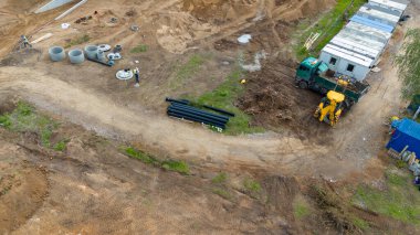 Ağır makineler ve inşaat malzemeleri olan bir inşaat alanının havadan görüntüsü.