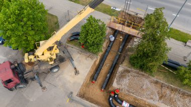 Yeraltına büyük borular döşenmiş bir vinç ve inşaat alanının havadan görüntüsü..