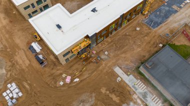 Kısmen inşa edilmiş ve etrafını toprakla çevreleyen bir inşaat alanının havadan görüntüsü..
