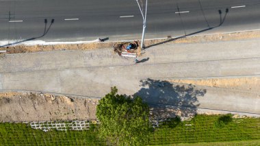 İşçi ve ekipmanlı bir yol şantiyesinin havadan görüntüsü.